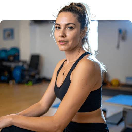 Mara V. seated in a warmly lit gym